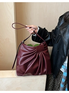 Detail of burgundy pleated underarm bag showing premium PU leather and metal buckle