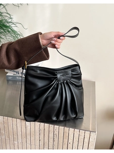Detail of black pleated hobo bag with Fashion & Bags Leather logo on matte PU surface