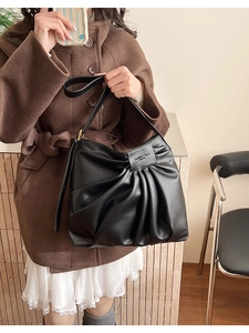 Detailed view of black pleated underarm bag showing premium soft PU leather and brand tag