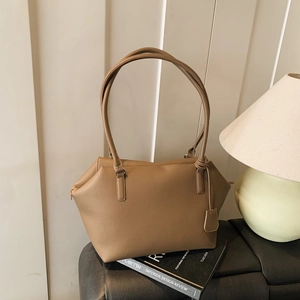 Brown lychee leather tote bag with thin shoulder straps shown on a book background