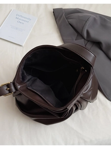 Detail view of large dark brown pleated tote bag interior with zipper pockets and lining