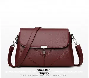 Detail view of wine red crossbody bag with lychee texture and leaf pendant charm
