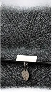 Close-up of litchi texture black leather bag with silver leaf pendant and hardware