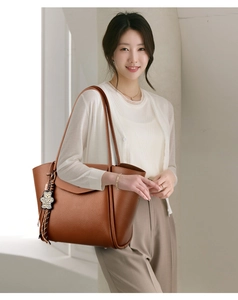 Detailed macro view of the brown lychee pattern leather tote bag with leopard bear charm