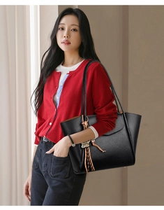 Detail of black pebbled leather tote bag with stylish leopard print tassel charm