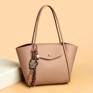 Detailed shot of apricot lychee grain leather tote bag with a leopard bear charm