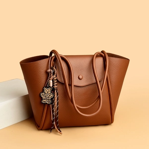 Classic brown leather tote bag with subtle lychee texture and leopard bear charm decoration
