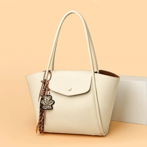 Detail of beige lychee leather tote bag featuring a cute leopard bear and tassel charm