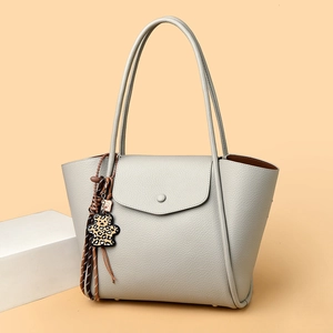 Close-up of cream soft leather tote with leopard bear charm and tassel detail