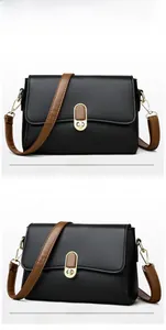 Detail view of black pebble leather shoulder bag with golden twist lock and brown strap