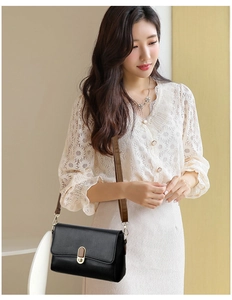 Fashionable black faux leather crossbody bag with gold lock worn by a model in lifestyle setting