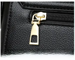 Detail of golden hardware zipper pull on black litchi textured leather shoulder bag
