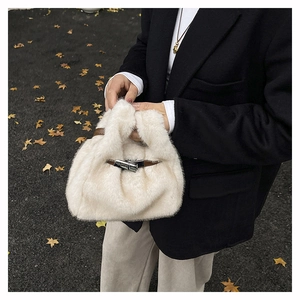 Detail of cream plush crossbody bag with brown leather strap and silver metal buckle