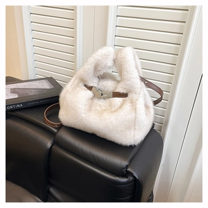 Detail of off-white faux fur handbag with brown leather strap and silver lock on sofa