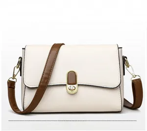 Detail of off-white lychee leather shoulder bag with brown strap and gold twist lock