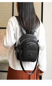 Detail eines schwarzen Mini-Rucksacks aus Kunstleder mit V-Steppung und silbernen Reißverschlüssen
