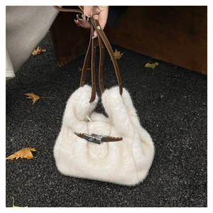 Detail of white faux fur handbag with brown leather strap and silver metal turn-lock