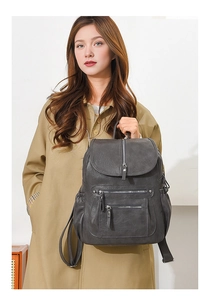 Detail of dark gray faux leather backpack with metallic zippers and front flap pockets