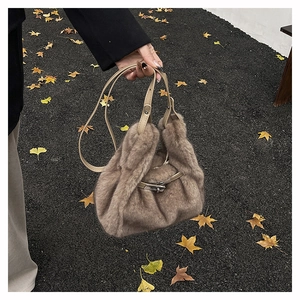 Detail of soft brown faux fur crossbody bag with silver metal twist lock on autumn street