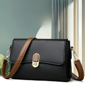 Detail of black lychee grain leather handbag with gold twist lock and brown strap