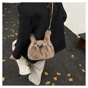 Detail of a brown faux fur crossbody bag with metal buckle and slim leather strap