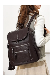 Side view of dark brown faux leather backpack with double front zippers on model