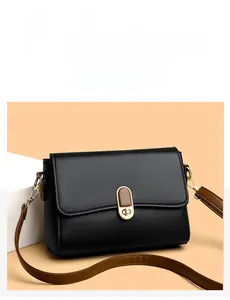 Detail of black lychee grain flap bag featuring a gold twist lock and slim brown strap