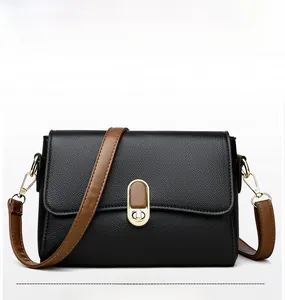 Close-up of black lychee grain leather handbag with gold twist lock and brown strap
