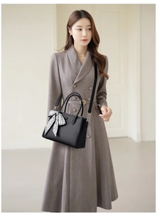 Detail of black pebbled leather handbag with decorative silk scarf on a trench coat model