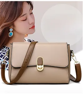 Detail of khaki pebbled leather shoulder bag with gold metal buckle and brown strap