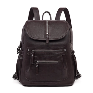 Detail of dark brown vintage backpack showing pebbled texture and silver zippers