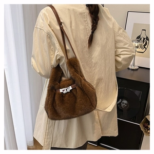 Detail of soft brown faux fur handbag featuring a classic metal twist lock and leather strap
