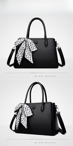 Detail of black lychee grain leather handbag with decorative silk scarf and shoulder strap
