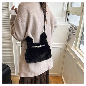 Detail of black faux fur shoulder bag with silver buckle worn over a beige winter coat