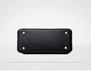 Close-up of litchi texture leather handbag base with four silver protective metal feet