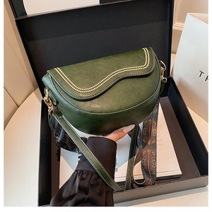 Détail du sac selle vert foncé avec bords ondulés et sangle géométrique colorée