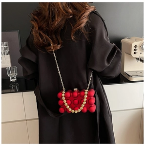 Detail of red acrylic bubble bag with gold chain strap and beaded handle for women