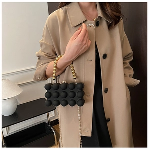 Detailed view of black acrylic box bag with 3D spherical texture and golden bead handle