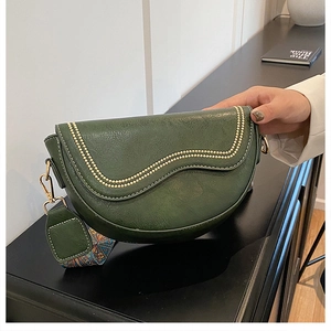 Détail du sac selle vert foncé avec perles métalliques et large bandoulière à motifs