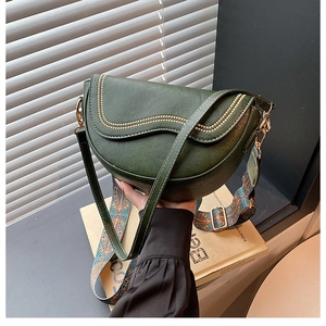 Détail du sac selle vert foncé avec rivets dorés et bandoulière style bohème
