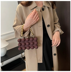 Detail of plum bubble texture acrylic evening bag with gold beaded handle and chain strap