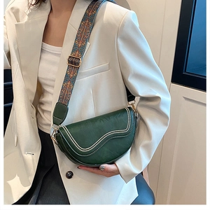Détail du sac selle vert foncé avec rivets ondulés et bandoulière jacquard colorée