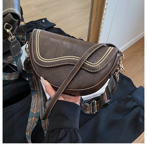 Gros plan sur un sac selle marron vintage avec coutures et bandoulière tissée