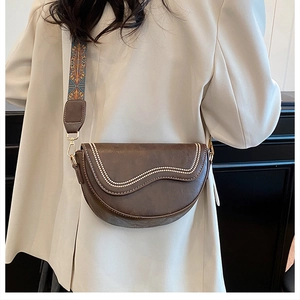 Détail d'une besace marron foncé avec bandoulière ethnique et broderie perlée ondulée