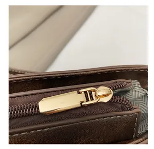 Détail de la fermeture éclair dorée et doublure à chevrons sur le sac marron foncé