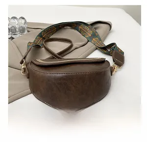 Détail d'un sac besace marron foncé avec une large bandoulière colorée de style ethnique