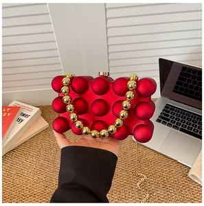 Detail of red bubble texture acrylic clutch bag with gold beaded handle and chain