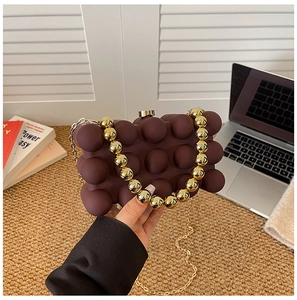 Detail of coffee brown bubble acrylic clutch bag with chunky gold bead handle and chain