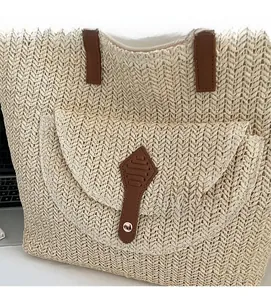 Détail d'un sac cabas en paille tissée avec rabat en cuir marron et fermoir