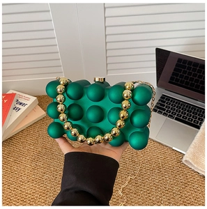 Detail of matte green acrylic clutch bag with bubble texture and gold beaded handle